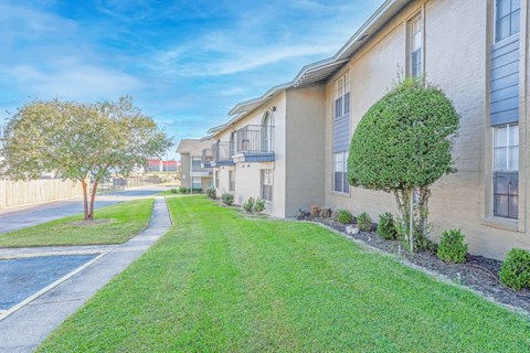 Apartment buildings with second-floor balconies and green grass outside   at The Creole Apartments in Shreveport, LA